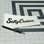Black Salty Cruiser script decal on backing paper beside a pen
